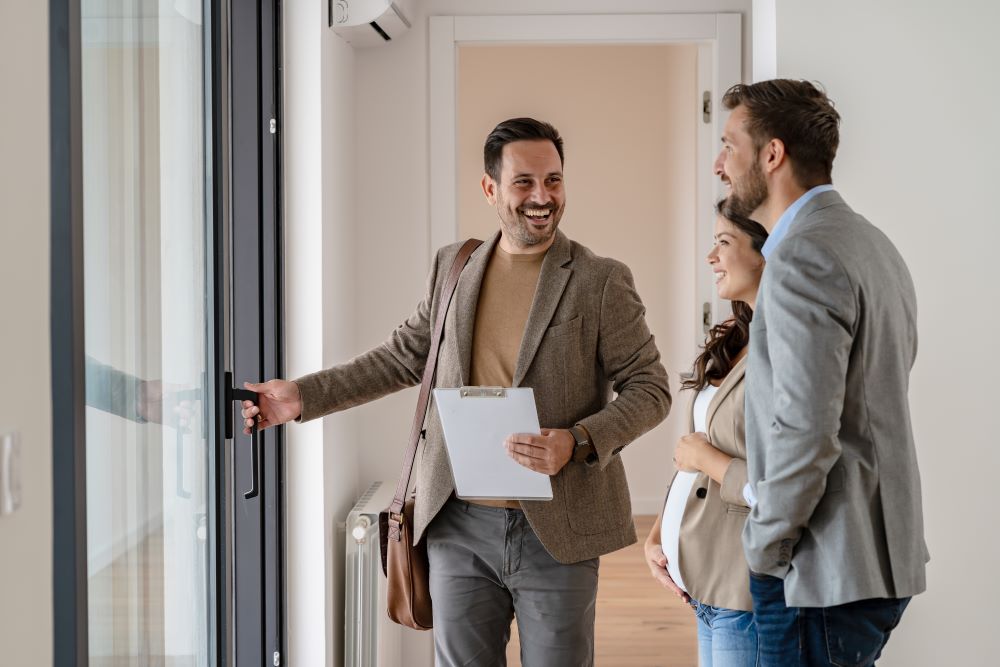 A relocating young couple with a real-estate agent visiting an apartment for sale or for rent. 